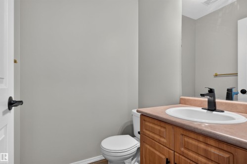 Bathroom featuring a wood-finish vanity with a built-in sink, a black faucet, and a wall mirror - 1816 36 Avenue Nw, Edmonton, AB - Indoor Photo Showing Bathroom