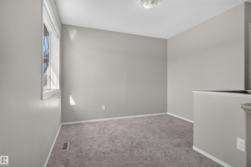 Neutral tone wall paint, textured carpet flooring, window with blinds, white trim, and ceiling-mounted light fixture - 1816 36 Avenue Nw, Edmonton, AB - Indoor Photo Showing Other Room