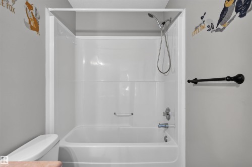 White bathtub and shower combination with a handheld showerhead and wall-mounted towel bar - 1816 36 Avenue Nw, Edmonton, AB - Indoor Photo Showing Bathroom