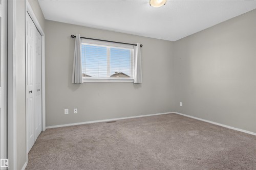 Neutral wall color, carpet flooring, window with blinds, bi-fold closet doors, and ceiling-mounted light fixture - 1816 36 Avenue Nw, Edmonton, AB - Indoor Photo Showing Other Room
