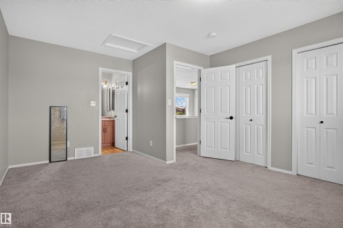 Neutral gray wall color, textured carpeting, white trim, white paneled doors, and a bathroom with a wood-finish vanity - 1816 36 Avenue Nw, Edmonton, AB - Indoor