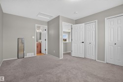 Neutral gray wall color, textured carpeting, white trim, white paneled doors, and a bathroom with a wood-finish vanity - 