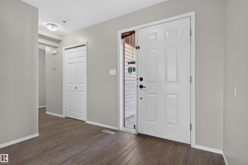 Entryway featuring a white paneled door, wood-finish flooring, light grey walls, white trim, and a flush mount ceiling light - 1816 36 Avenue Nw, Edmonton, AB - Indoor Photo Showing Other Room