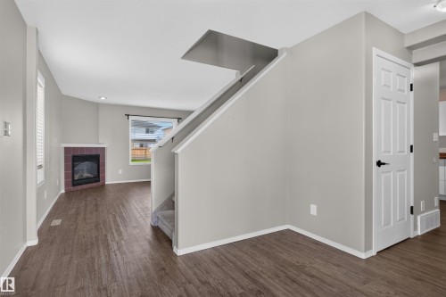 Wood-finish flooring, staircase with carpeted treads, built-in fireplace with a tiled surround, recessed lighting, and white paneled interior doors - 1816 36 Avenue Nw, Edmonton, AB - Indoor Photo Showing Other Room With Fireplace