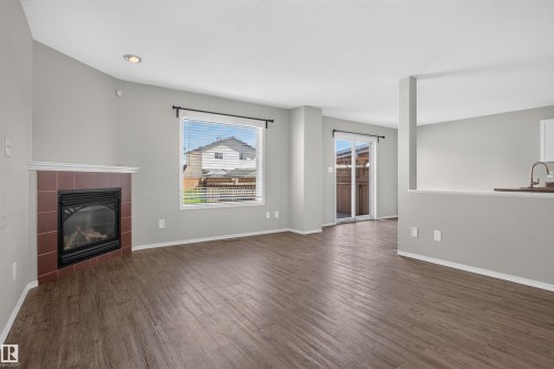 Wood-finish flooring, recessed lighting, and a corner fireplace with a tile surround - 1816 36 Avenue Nw, Edmonton, AB - Indoor Photo Showing Living Room With Fireplace