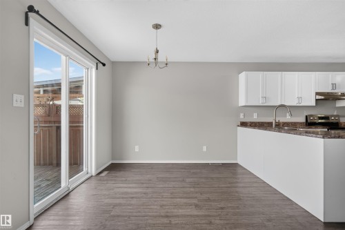 Spacious kitchen featuring white cabinetry, dark countertops, and a stainless steel sink - 1816 36 Avenue Nw, Edmonton, AB - Indoor Photo Showing Kitchen