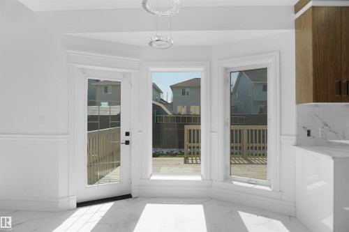 White marble-look tile flooring, white walls with wainscoting, white trim, wood-finish cabinetry, and a white marble-look countertop with matching backsplash - 6823 18 Avenue Sw, Edmonton, AB - Indoor Photo Showing Other Room