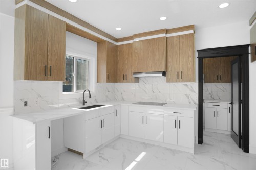 Contemporary kitchen featuring two-tone cabinetry, white countertops, a black sink with a matte black faucet, and recessed lighting - 6823 18 Avenue Sw, Edmonton, AB - Indoor Photo Showing Kitchen