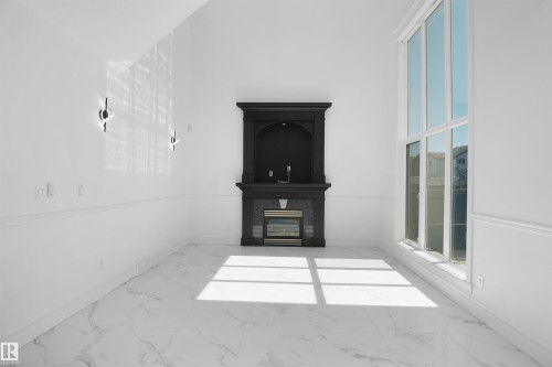 Vaulted ceiling, full-height window, fireplace with mantel, marble-look flooring, and wall sconces - 6823 18 Avenue Sw, Edmonton, AB -  With Exterior