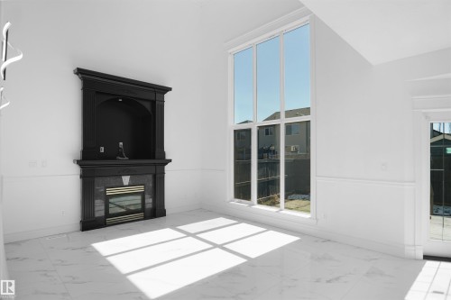 Dramatic two-story windows, elegant fireplace with mantel, white marble-look flooring, wainscoting, and a glass-paneled door - 6823 18 Avenue Sw, Edmonton, AB -  With Fireplace
