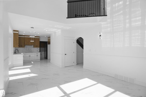 Recessed lighting throughout, marble-look flooring, arched doorway, a balcony with metal railings, and a full kitchen - 6823 18 Avenue Sw, Edmonton, AB - Indoor Photo Showing Other Room