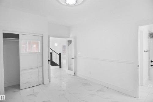 White tile flooring, mirrored closet doors, paneled walls, and a recessed ceiling light fixture - 6823 18 Avenue Sw, Edmonton, AB - Indoor Photo Showing Other Room
