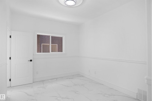 White interior featuring marble-look tile flooring, white walls, and a white paneled door with black hardware - 6823 18 Avenue Sw, Edmonton, AB - Indoor Photo Showing Other Room