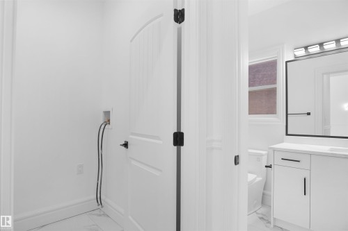 White paneled interior door with black hardware, white walls, and a white baseboard - 6823 18 Avenue Sw, Edmonton, AB - Indoor Photo Showing Other Room