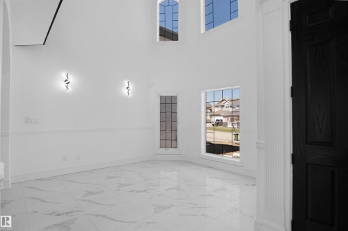 Soaring ceilings complemented by multiple windows, a paneled black door, and elegant wall sconces - 6823 18 Avenue Sw, Edmonton, AB - Indoor