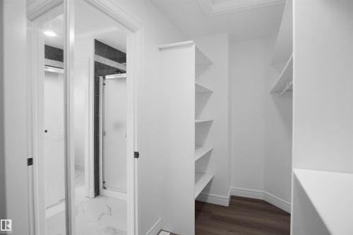Walk-in closet with built-in shelving, hanging rod, and wood-finish flooring - 6823 18 Avenue Sw, Edmonton, AB - Indoor With Storage