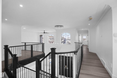 Upper-level landing featuring wood-finish flooring, wrought iron railings, arched window details, and recessed lighting - 6823 18 Avenue Sw, Edmonton, AB - Indoor Photo Showing Other Room