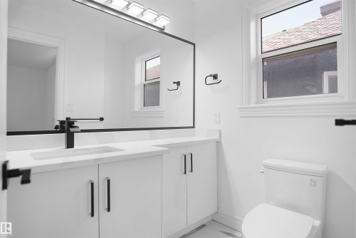 White vanity with flat panel cabinetry, black hardware, and a white countertop with an integrated sink - 6823 18 Avenue Sw, Edmonton, AB - Indoor Photo Showing Bathroom