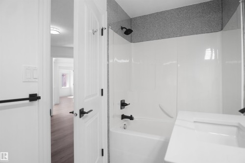 Bathroom featuring a white integrated sink vanity, black hardware throughout, and a shower/tub combination with textured wall surround - 6823 18 Avenue Sw, Edmonton, AB - Indoor Photo Showing Bathroom
