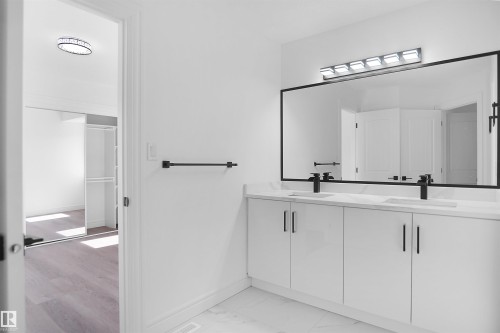 Dual vanity with white cabinetry and integrated sinks, matte black hardware and faucets, and a large wall-mounted mirror - 6823 18 Avenue Sw, Edmonton, AB - Indoor