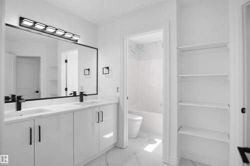 Dual vanity with white cabinetry, black hardware, and an oversized mirror - 6823 18 Avenue Sw, Edmonton, AB - Indoor Photo Showing Bathroom