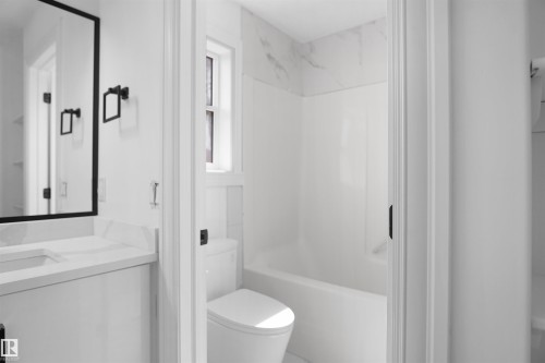 Vanity with a rectangular undermount sink, stone countertop, and black framed mirror - 6823 18 Avenue Sw, Edmonton, AB - Indoor Photo Showing Bathroom
