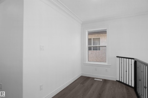 Wood-finish flooring with white baseboards, crown molding, and a double-pane window - 6823 18 Avenue Sw, Edmonton, AB - Indoor Photo Showing Other Room