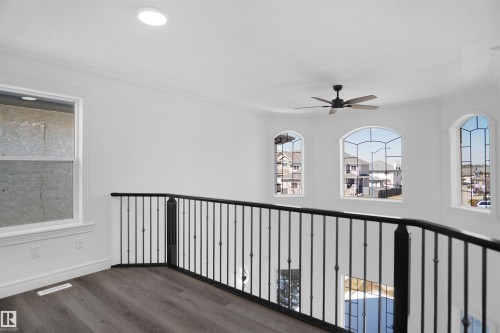 Loft area featuring wood-finish flooring, wrought iron railing, arched windows, and a ceiling fan - 6823 18 Avenue Sw, Edmonton, AB - Indoor Photo Showing Other Room
