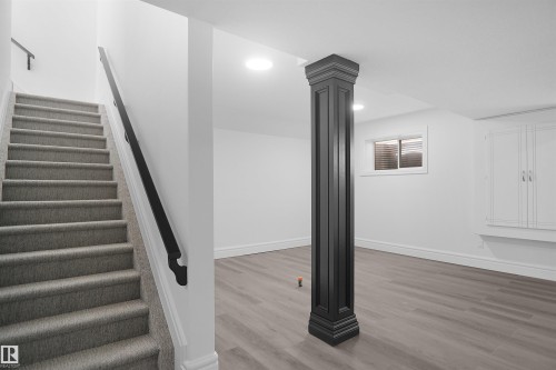 Staircase with carpeted treads and black handrail, recessed lighting, wood-finish flooring, built-in cabinetry, and a window with blinds - 6823 18 Avenue Sw, Edmonton, AB - Indoor Photo Showing Other Room
