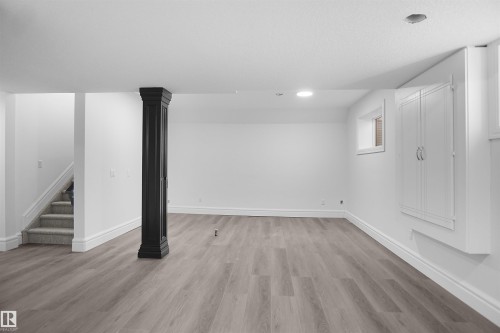 Spacious room with wood-finish flooring, recessed lighting, and a built-in storage cabinet - 6823 18 Avenue Sw, Edmonton, AB - Indoor Photo Showing Other Room