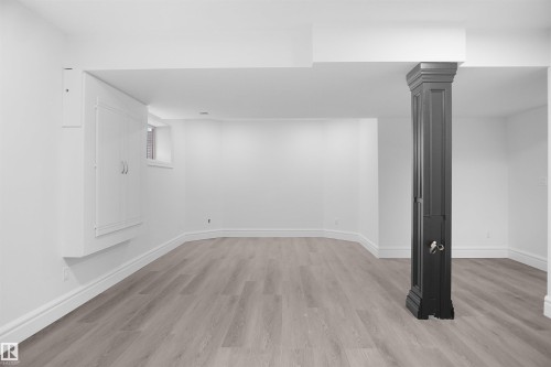 Spacious room featuring light wood-finish flooring, white walls, and a decorative column - 6823 18 Avenue Sw, Edmonton, AB - Indoor