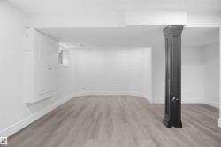 Spacious room featuring light wood-finish flooring, white walls, and a decorative column - 