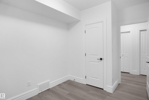 Freshly painted walls, wood-finish flooring, and white trim - 6823 18 Avenue Sw, Edmonton, AB - Indoor Photo Showing Other Room