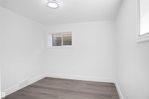 White painted walls with wood-finish flooring, featuring a flush-mount ceiling light and a single window - 6823 18 Avenue Sw, Edmonton, AB - Indoor Photo Showing Other Room