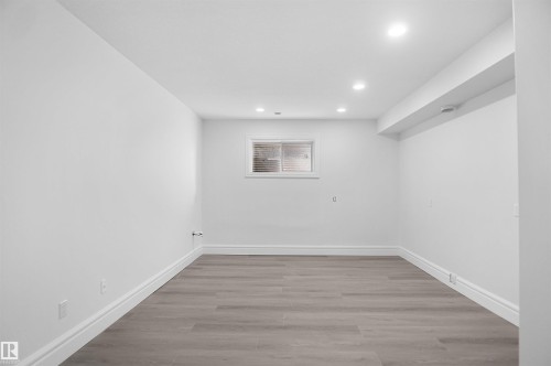 Recessed lighting, light gray wood-finish flooring, and a single window with horizontal blinds - 6823 18 Avenue Sw, Edmonton, AB - Indoor Photo Showing Other Room