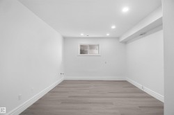 Recessed lighting, light gray wood-finish flooring, and a single window with horizontal blinds - 
