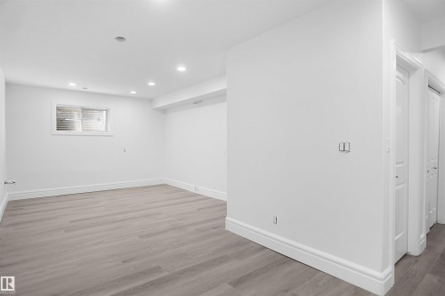 Recessed lighting illuminates this space featuring wood-finish flooring, a window, and white trim throughout - 6823 18 Avenue Sw, Edmonton, AB - Indoor Photo Showing Other Room