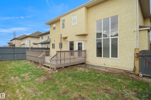 Private backyard space featuring a wood deck with railings, a rear entry door, and a large multi-pane window - 6823 18 Avenue Sw, Edmonton, AB - Outdoor With Exterior