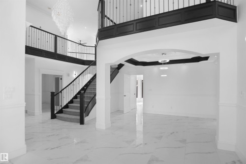 Grand two-story foyer with a curved staircase featuring wrought iron balusters and carpeted treads - 6823 18 Avenue Sw, Edmonton, AB - Indoor Photo Showing Other Room