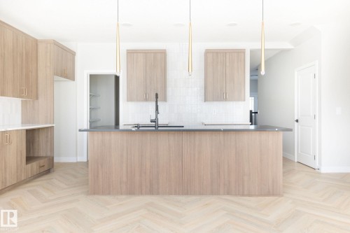 Kitchen with light wood-finish cabinetry, dark countertops, and a white tile backsplash - 24 Clichy Close, St. Albert, AB - Indoor Photo Showing Kitchen