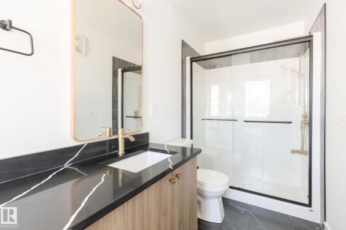 Vanity with a black stone countertop, integrated sink, and gold-finish faucet - 24 Clichy Close, St. Albert, AB - Indoor Photo Showing Bathroom
