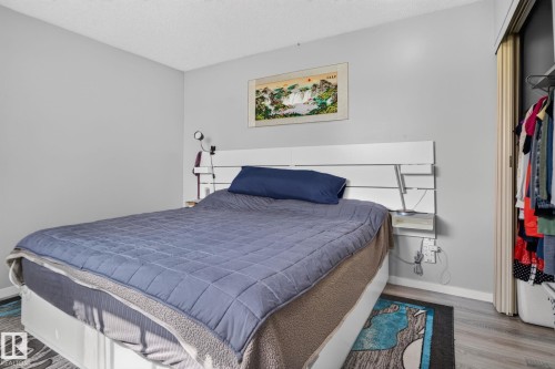 Light gray walls, wood-finish flooring, and a built-in closet with bifold doors - 8031 27 Avenue Nw, Edmonton, AB - Indoor Photo Showing Bedroom