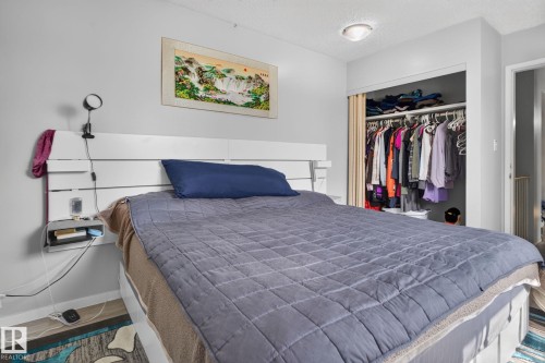 Integrated headboard with shelving, semi-flush ceiling light fixture, wall-mounted light fixture, and closet with sliding panel door - 8031 27 Avenue Nw, Edmonton, AB - Indoor Photo Showing Bedroom