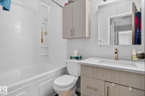 Modern bathroom featuring a wood-finish vanity with an integrated sink and white quartz countertop, brushed gold faucet, and medicine cabinet with mirror - 8031 27 Avenue Nw, Edmonton, AB - Indoor Photo Showing Bathroom