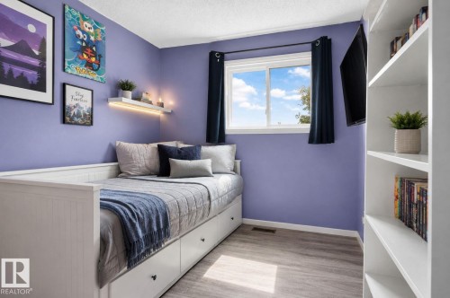 Built-in shelving, wood-finish flooring, and a window with white trim - 8031 27 Avenue Nw, Edmonton, AB - Indoor Photo Showing Bedroom