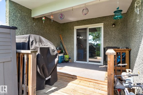 Covered patio with textured exterior walls and a sliding glass door - 8031 27 Avenue Nw, Edmonton, AB - Outdoor With Exterior