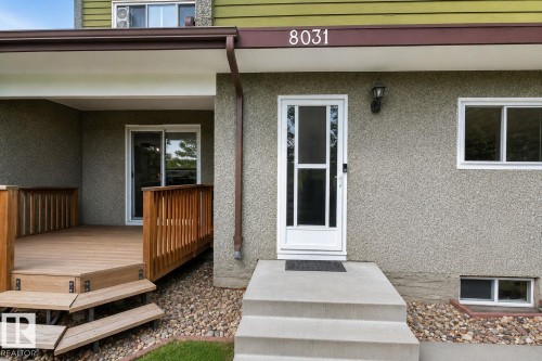 Covered front entry with concrete steps and a screen door, featuring an exterior light fixture, house numbers, and a sliding glass door opening to a private deck - 8031 27 Avenue Nw, Edmonton, AB - Outdoor With Exterior