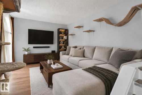 Light wood-finish flooring, built-in shelving with integrated lighting, and a wall-mounted entertainment console - 8031 27 Avenue Nw, Edmonton, AB - Indoor Photo Showing Living Room