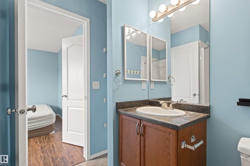 Bathroom vanity with a built-in sink, dark countertop, and wood-finish cabinetry - 9118 Scott Crescent Nw, Edmonton, AB - Indoor Photo Showing Bathroom