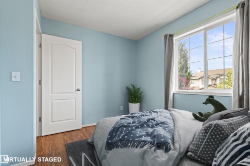 Recessed panel interior door, wood-finish flooring, and a large window with grid panes - 9118 Scott Crescent Nw, Edmonton, AB - Indoor Photo Showing Bedroom